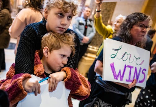 Hildie Edwards with sister Dahlia take time from school to advocate for the "trans refuge" bill up for vote in the Senate at the Capitol in St. Paul, Minn., on Friday, April 21, 2023. In the background are signs opposing and supporting the issue. Hildie Edwards is a transgender activist who has helped pass legislation making Minnesota a refuge for transgender individuals. ] RICHARD TSONG-TAATARII • richard.tsong-taatarii@startribune.com