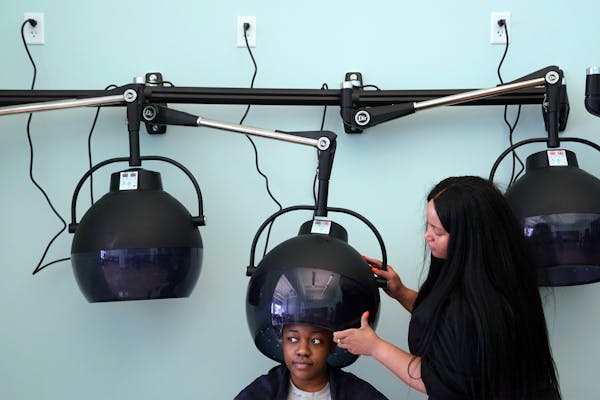 Sasha Dennis of Minneapolis sat under a dryer after getting her hair washed by stylist Andrewa Murphy, right, Wednesday morning at the Beauty Lounge.