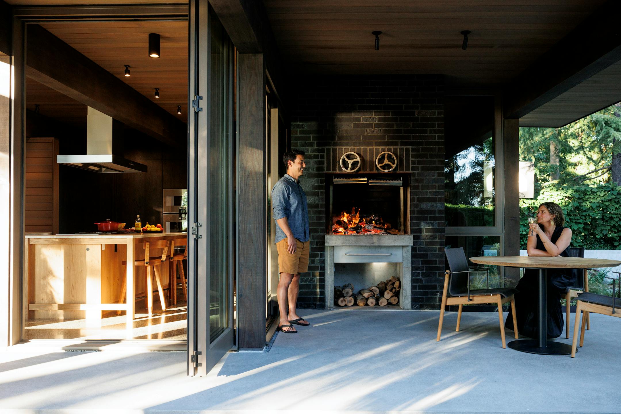 Sonya Schneider and Stuart Nagae in the new indoor/outdoor kitchen extension of their home, built in 1933 and now designated as a historical landmark, on Puget Sound in Seattle's Ballard neighborhood, on Aug. 3. 2023. The couple found a way to marry a contemporary kitchen extension to the Scandinavian vernacular architecture of the house, built by a Norwegian sea captain as a replica of his childhood home. (Brooke Fitts/The New York Times)