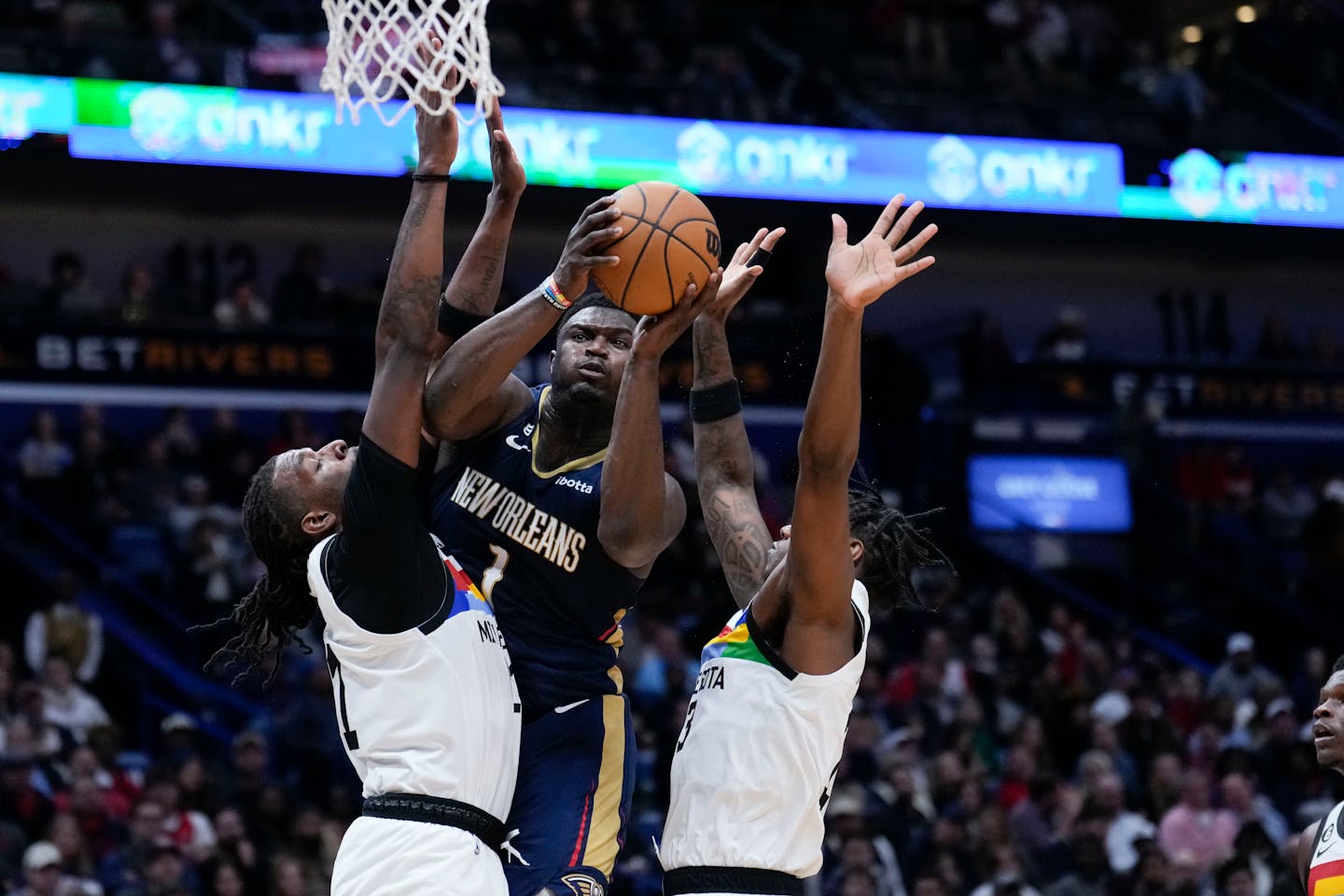 New Orleans Pelicans forward Zion Williamson (1) goes to the basket between Minnesota Timberwolves center Naz Reid, left, and forward Nathan Knight in the second half of an NBA basketball game in New Orleans, Wednesday, Dec. 28, 2022. Williamson had a career high 43 points and the Pelicans won 119-118. (AP Photo/Gerald Herbert)