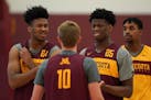 Gophers forward Eric Curry (24) and center Daniel Oturu (25) joked with guard Brady Rudrud (10) during Thursday's practice.
