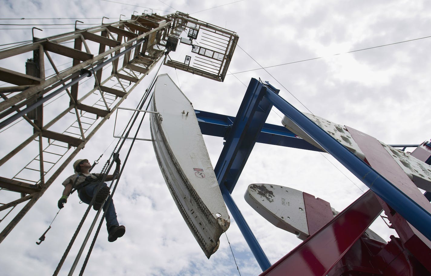 FILE - In this July 26, 2011, file photo, a worker hangs from an oil derrick outside of Williston, N.D. State data show that 1 billion barrels of oil have been produced from the rich Bakken shale formation in western North Dakota and eastern Montana. Data show that North Dakota has tallied 852 million barrels of Bakken crude, and Montana has produced about 151 million barrels. (AP Photo/Gregory Bull, File) ORG XMIT: CER603