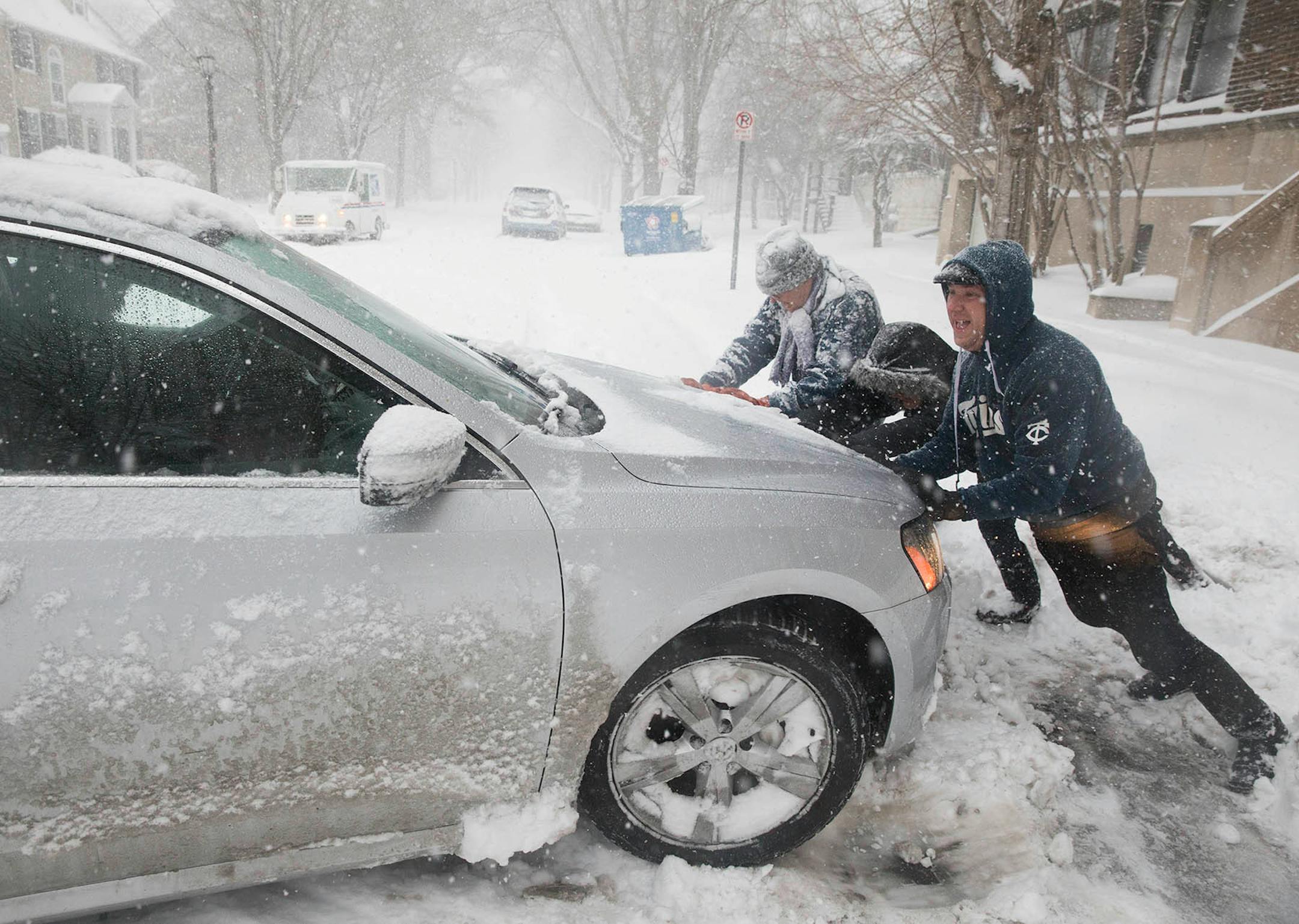 David Maruska, right, gets some help from neighbors getting his wife Mikki's car out of the snow in St. Paul.