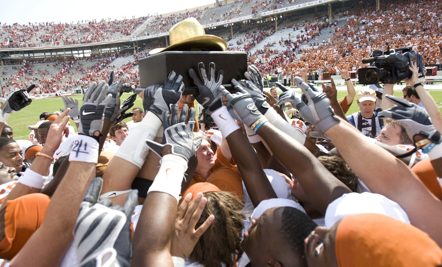 Texas coach Mack Brown, center under trophy, and the Texas Longhorns celebrate their 45-35 win over Oklahoma win with the "Golden Hat Trophy" after an NCAA college football game in Dallas, Saturday, Oct 11, 2008. (AP Photo/ University of Texas, Jim Sigmon, Pool) ** POOL PHOTO ** ORG XMIT: DNB140