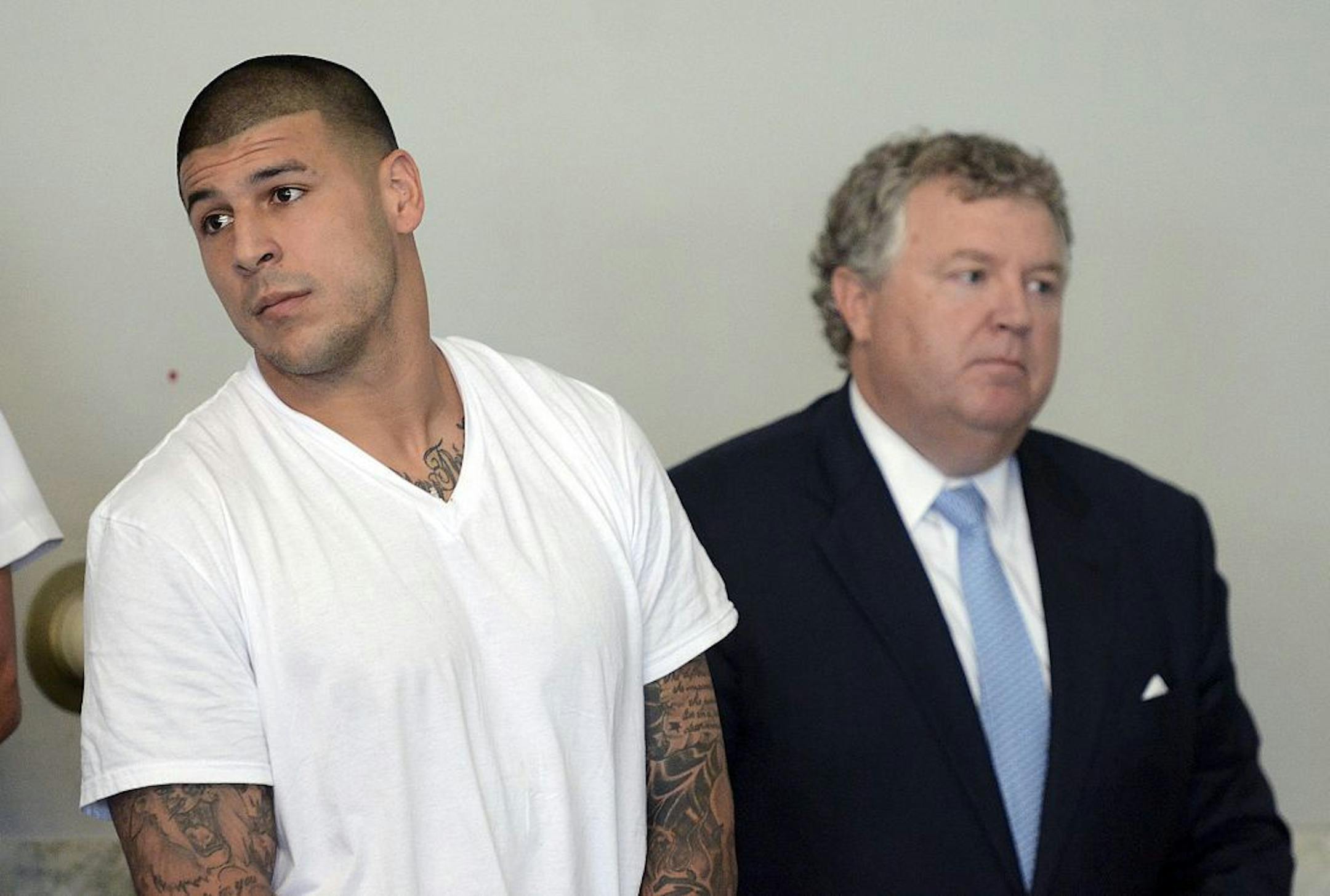 Former New England Patriots tight end Aaron Hernandez, left, stands with his attorney Michael Fee, right, during arraignment in Attleboro District Court Wednesday, June 26, in Attleboro, Mass.