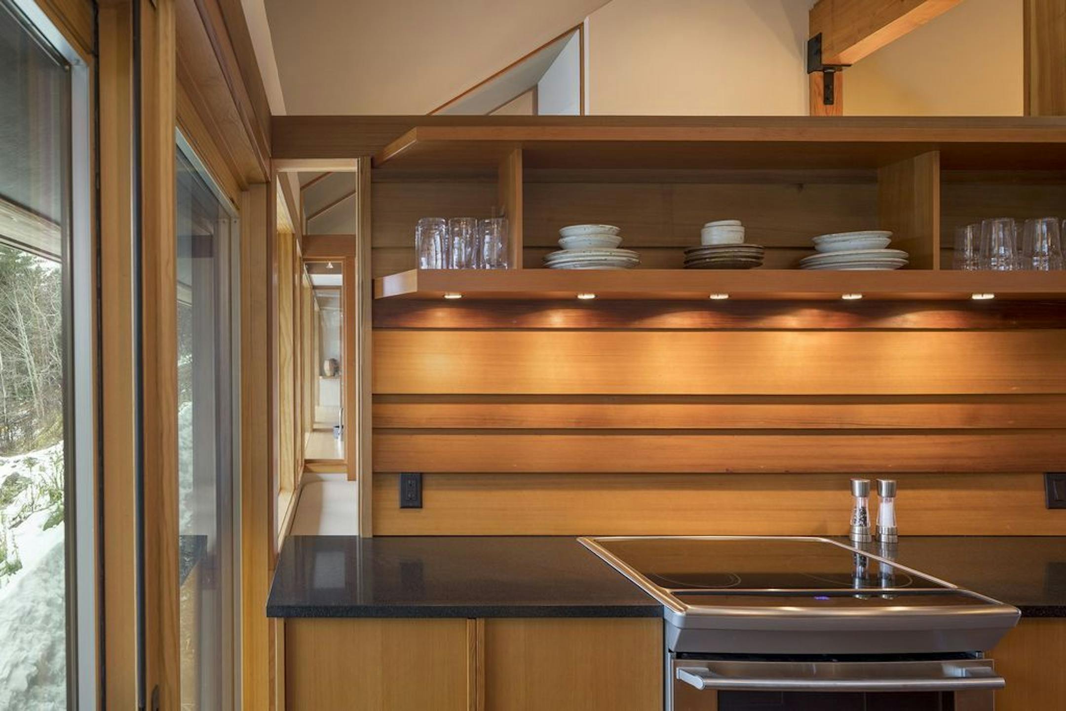 In the kitchen, an open slot along the wall that spans to the back bedroom shoots light through the cabin.