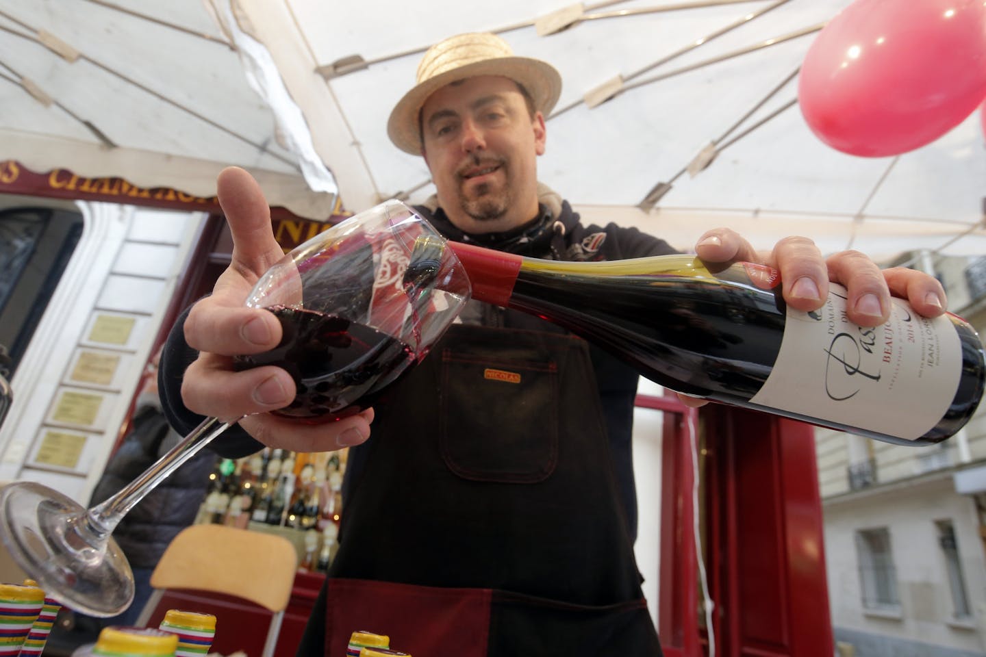 A wine storekeeper pours Beaujolais Nouveau wine in a glass during a presentation in a wine shop in Paris, Thursday Nov. 20, 2014. The wine world�s best known party is beginning, the ritual uncorking of Beaujolais Nouveau on the third Thursday in November.