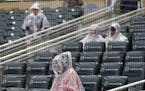 An usher and some rain-protected fans wait for a baseball game between the Minnesota Twins and the Chicago White Sox on Friday, April 14, 2017, in Min