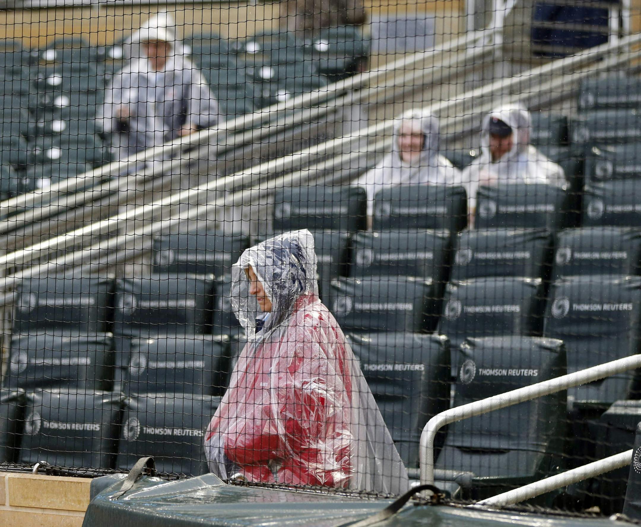 An usher and some rain-protected fans wait for a baseball game between the Minnesota Twins and the Chicago White Sox on Friday, April 14, 2017, in Minneapolis. (AP Photo/Jim Mone)