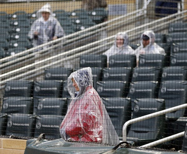 An usher and some rain-protected fans wait for a baseball game between the Minnesota Twins and the Chicago White Sox on Friday, April 14, 2017, in Min