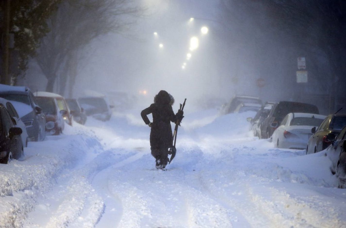 A woman walks down snow-covered Maverick Street in the East Boston neighborhood of Boston, Thursday, Jan. 4, 2018, as a huge winter storm roared up the East Coast with hurricane-force winds, heavy snow and coastal flooding.