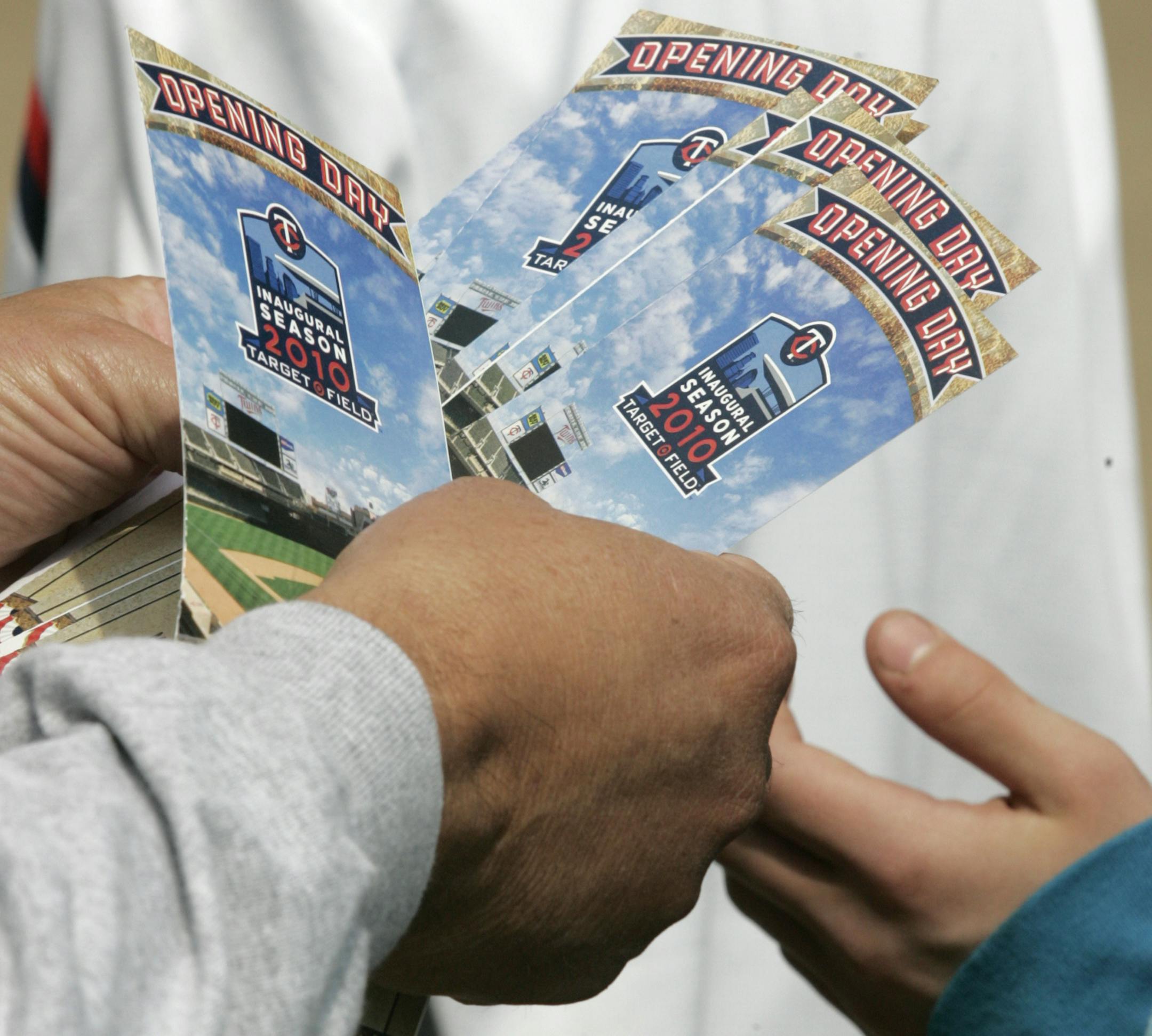 A fan hands out tickets as they enter Target Field for the Twins' home opener baseball game against the Boston Red Sox, Monday, April 12, 2010 in Minneapolis. (AP Photo/Paul Battaglia)