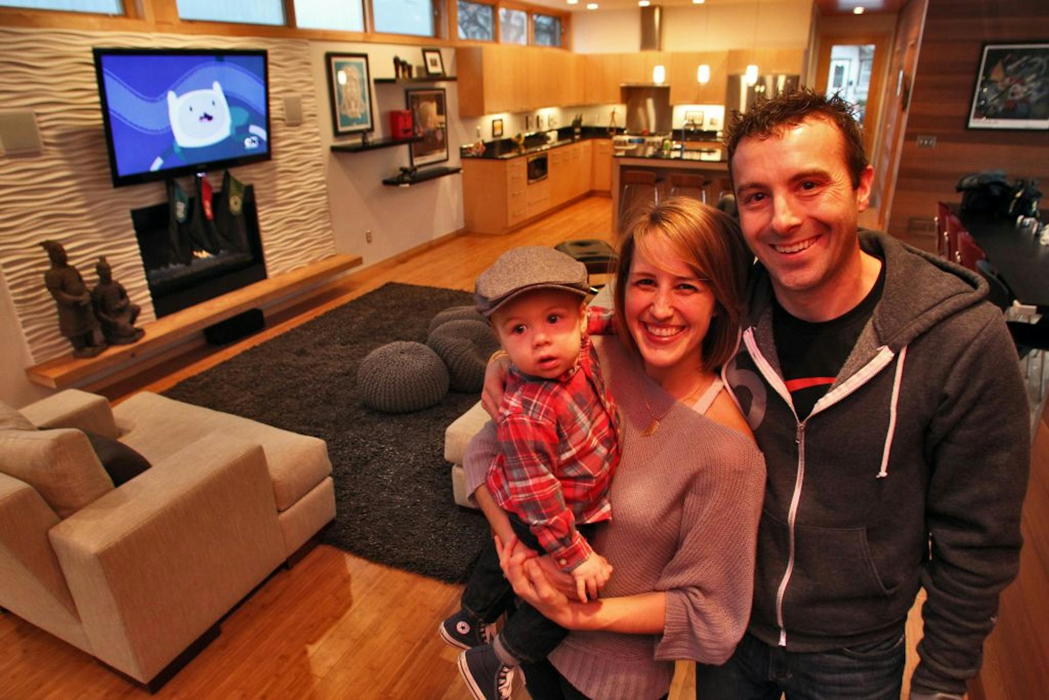 Erinn and Shane Farrell own a contemporary green home in south Minneapolis designed by architect Eric Odor. Erinn and Shane Farrell with son Oscar Farrell, 2 with the lower floor family living area and kitchen in background.
