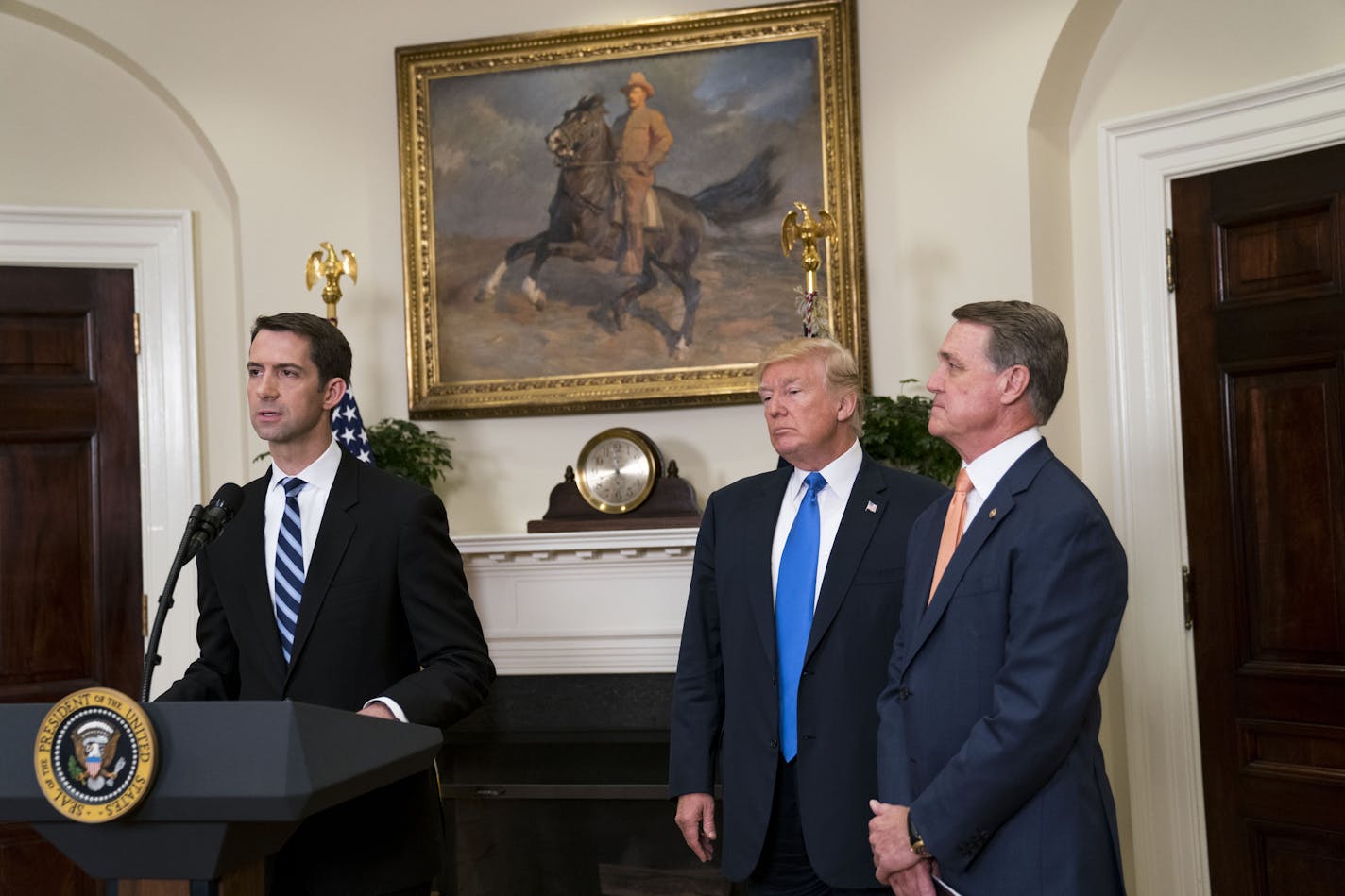 Sen. Tom Cotton (R-Ark.) discusses the Raise Act, immigration legislation he and Sen. David Perdue (R-Ga.), right, are sponsoring, with President Donald Trump at the White House in Washington, Aug. 2, 2017. The bill would overhaul decades of immigration policy by replacing a system that favors family ties in deciding who can move to the United States legally with merit-based preferences based on skills and employability. (Doug Mills/The New York Times)