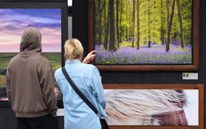 Patrons look over work by photographer Mike Behr at his booth on May 31, 2024 during the Edina Art Fair.