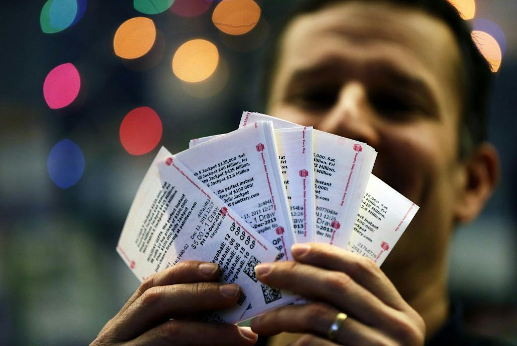 During an interview with the Associated Press, Chad Cuneo displays Mega Millions lottery tickets he purchased at a newsstand Friday, Dec. 13, 2013, in Philadelphia. Superstition didn't deter players hoping that Friday the 13th will bring them good luck in the Mega Millions game as heavy sales prompted lottery officials to boost the estimated jackpot to $425 million.