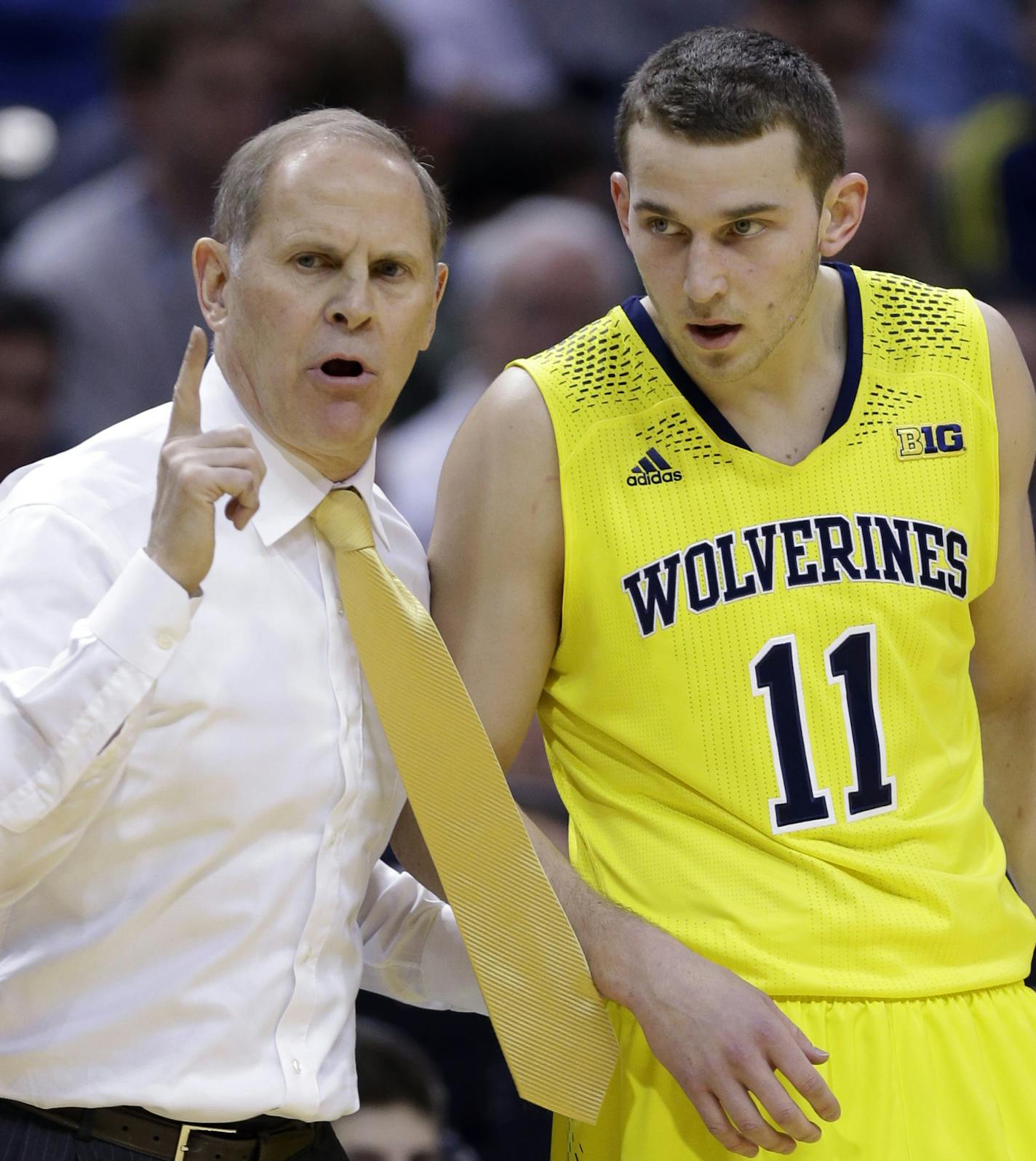 Michigan head coach John Beilein, left, talks to Michigan guard Nik Stauskas (11) in the first half of an NCAA college basketball game against Michigan State in the championship of the Big Ten Conference tournament on Sunday, March 16, 2014, in Indianapolis. (AP Photo/Michael Conroy)