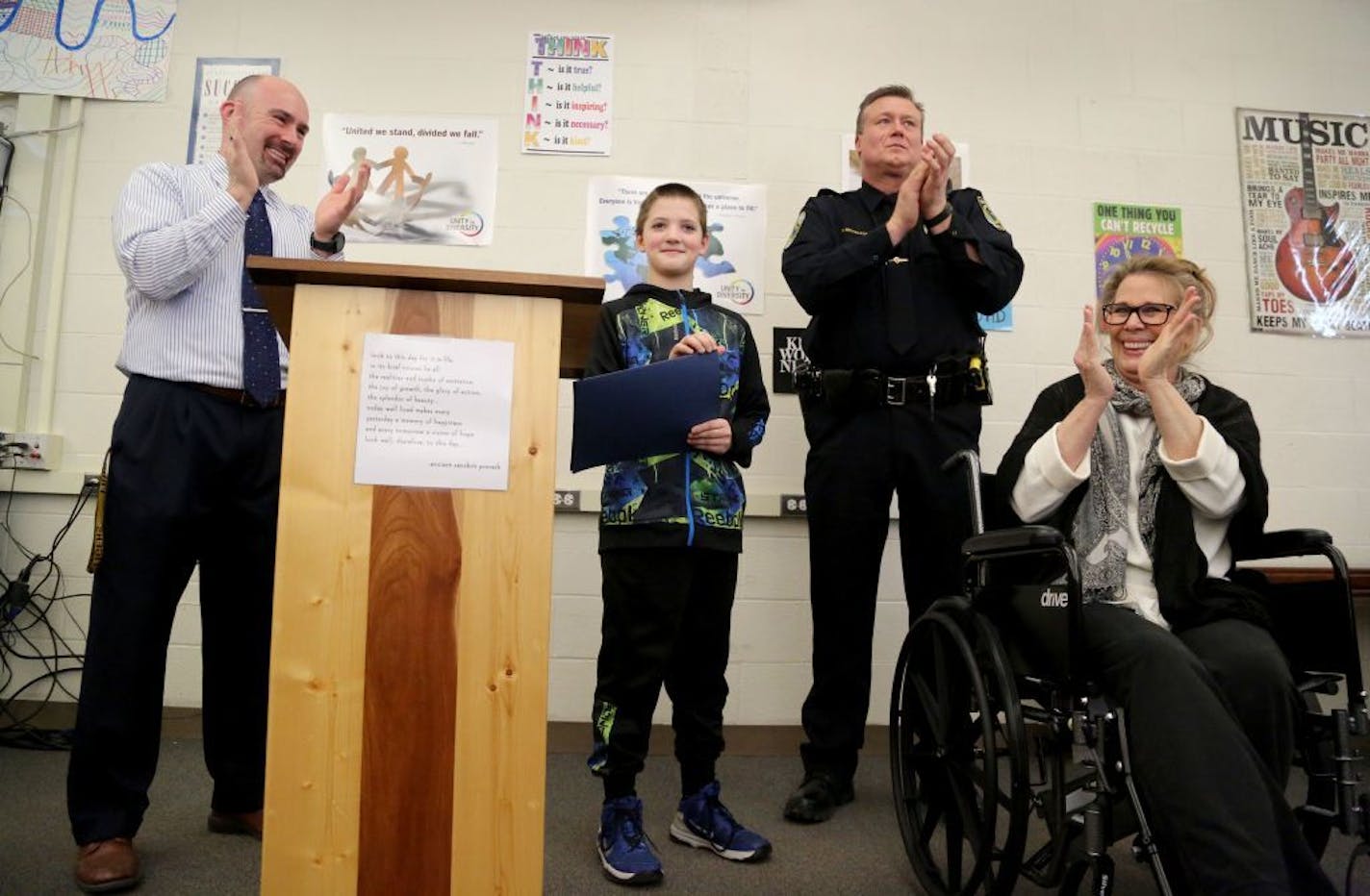 Fridley Middle School and Fridley Police Department recognized sixth grader Colby Hansen for his role in assisting injured homeowner Laurie Harms, who credits the boy with saving her life after she recently slipped and fell and shattered her hip and played for a few hours in the cold waiting for help before Hansen came to the rescue and called 911 and got medical assistance for Harms. Here, Harms, right to left, Fridley Police SRO Mark Mickelson, and Fridley Middle School principal Matthew Bouch