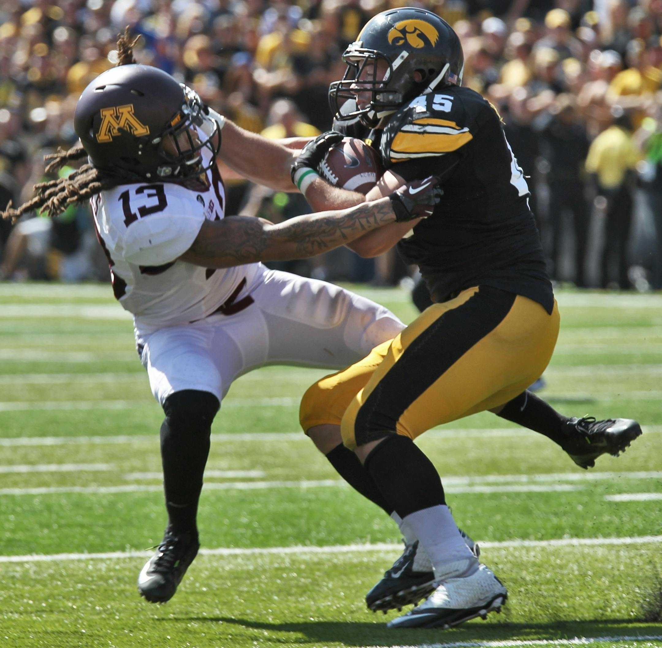 Minnesota Gophers vs. Iowa Hawkeyes football. Iowa won 31-13. Iowa running back Mark Weisman (45) pushed Minnestoa tackler Derrick Wells (13) aside as he picked up 2nd half rushing yards. (MARLIN LEVISON/STARTRIBUNE(mlevison@startribune.com