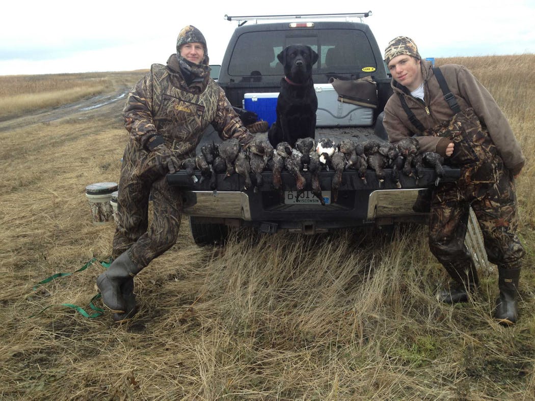 Del the black Labrador in 2013 with Cole Anderson, left, and Max Kelley, at Delta Marsh, Manitoba.