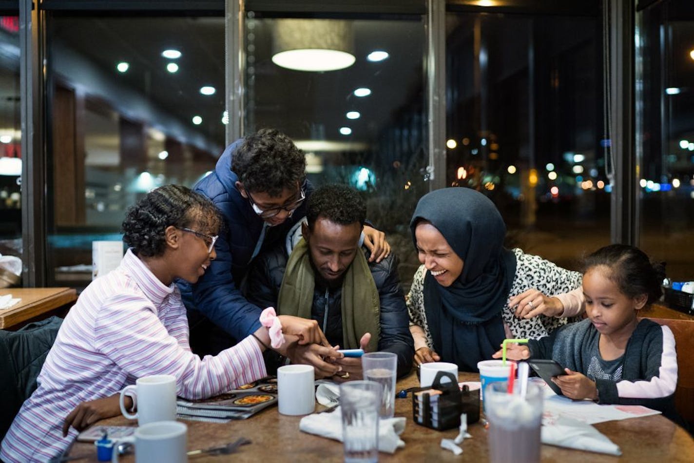 Rep. Ilhan Omar (D-Minn.) and her husband, Ahmed Hirsi, share a laugh during dinner in their usual booth at a Perkins Restaurant and Bakery with, from left, daughter Isra, son Adnan and daughter Ilwad in Minneapolis on Jan. 21, 2019. Omar has found, more than most of her freshman colleagues, that even in Minneapolis, maintaining a domestic routine can be difficult among the disruptions that come from her newfound celebrity.