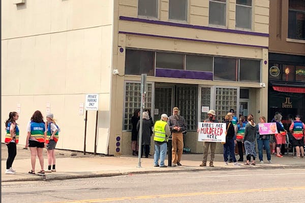 Protesters at North Dakota’s lone abortion clinic are flanked by patient escorts in rainbow-colored vests in May.