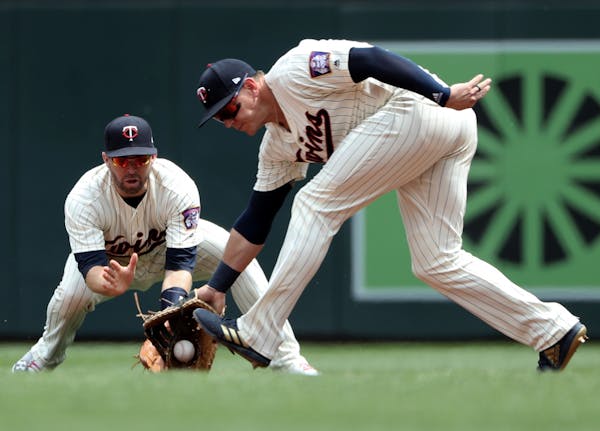 Minnesota Twins first baseman Logan Morrison reaches in front of second baseman Brian Dozier to scoop up a ground out by the Texas Rangers Jurickson P