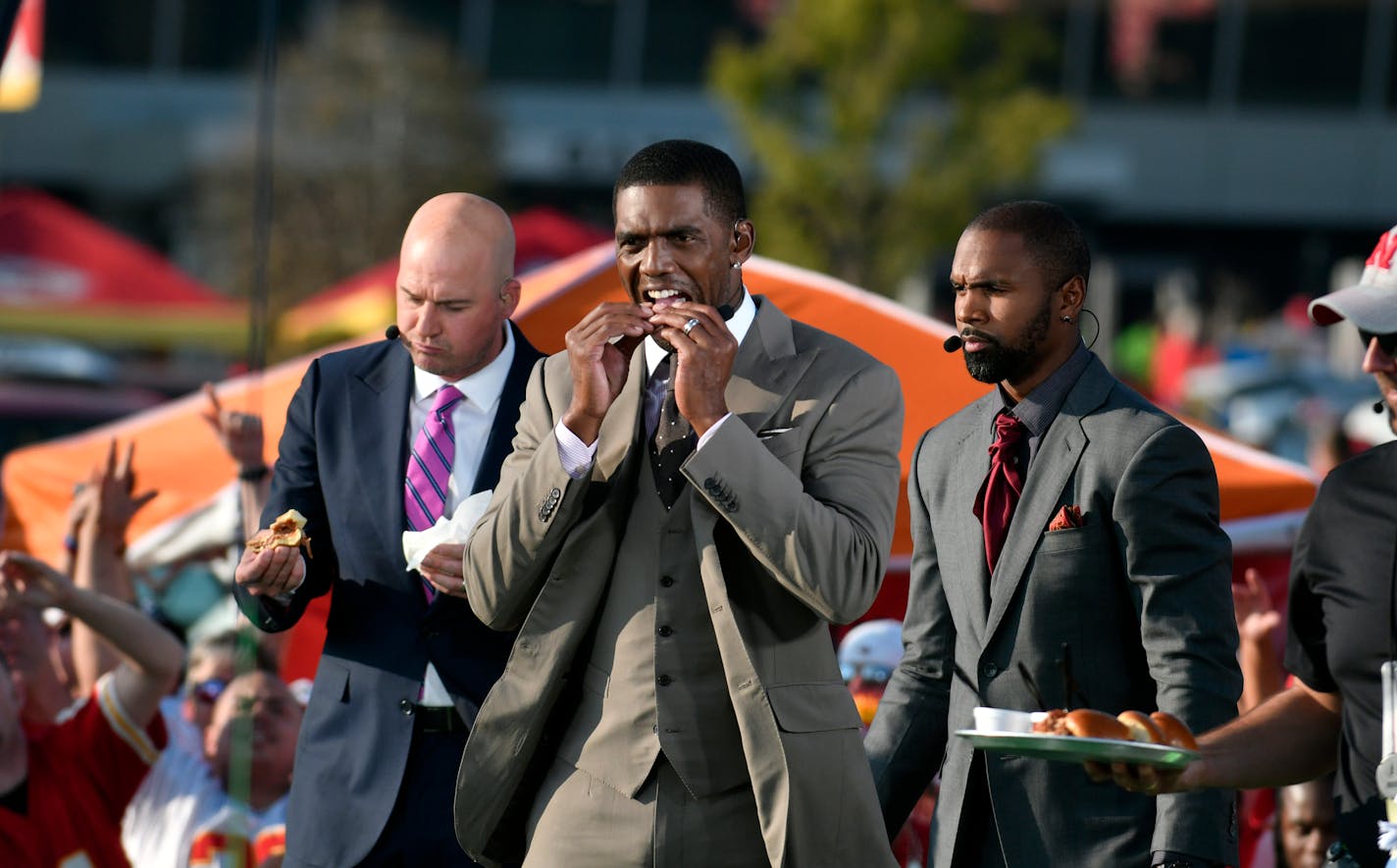 ESPN hosts from left: Matt Hasselbeck, Randy Moss and Charles Woodson sample food during a tailgating special outside Arrowhead Stadium before an NFL football game between the Kansas City Chiefs and the Washington Redskins, in Kansas City, Mo., Monday, Oct. 2, 2017. (AP Photo/Ed Zurga)