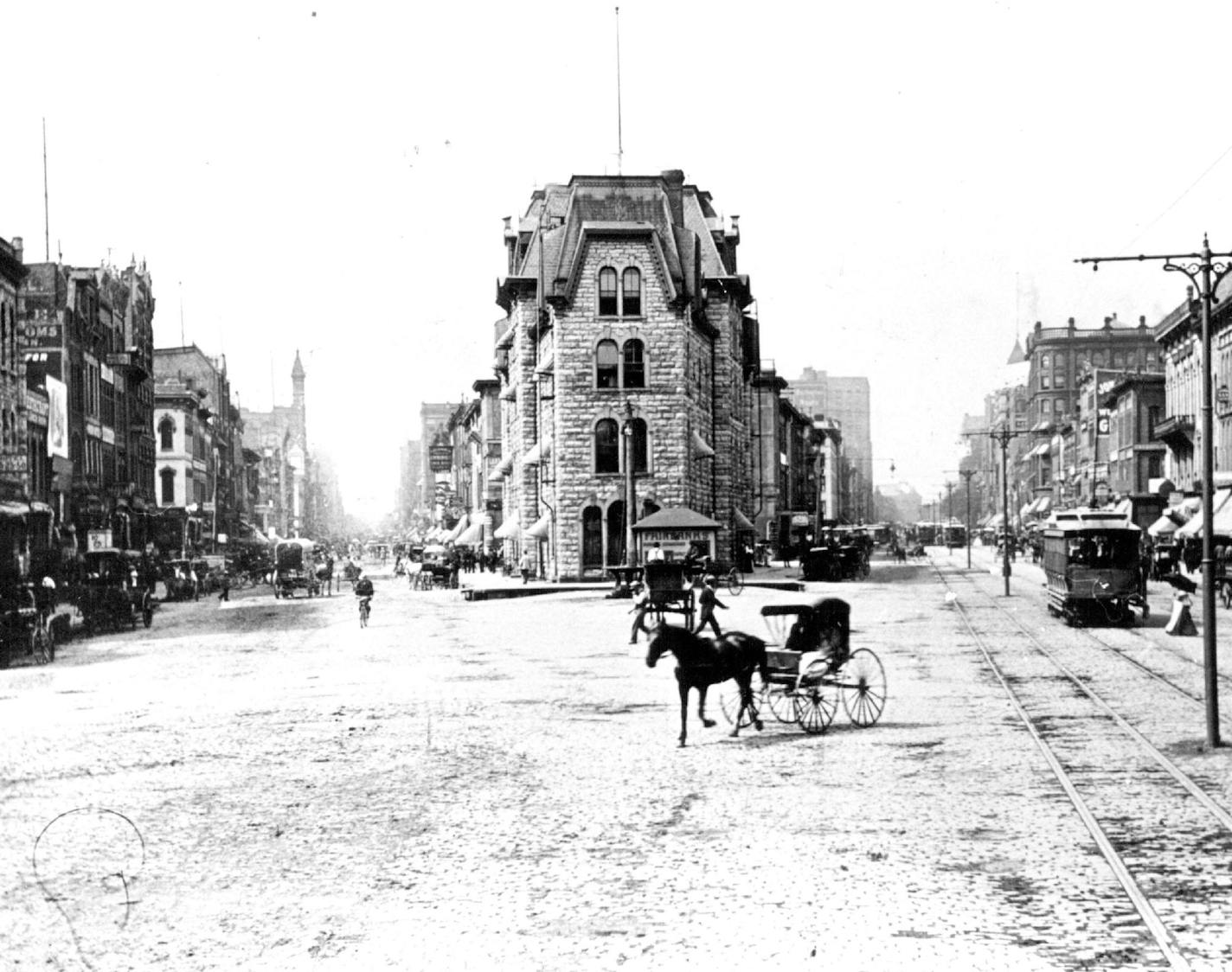 Conveyances abound -- bicycle, horse drawn carriage, bicycle, street cars -- in Bridge Square in 1895.