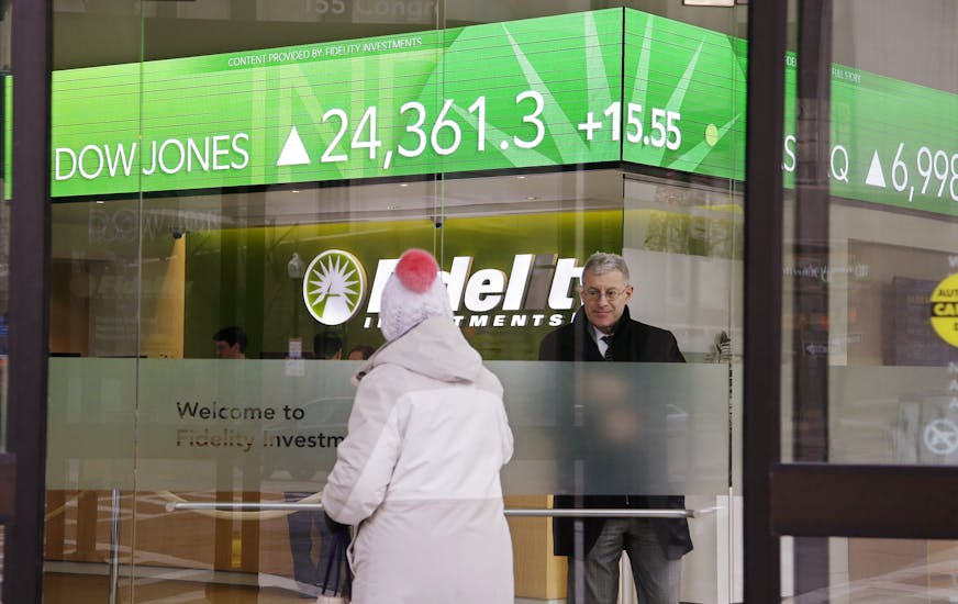 FILE - In this Feb. 6, 2018, file photo, a woman walks through the front doors at a Fidelity Investments office on Congress Street as the ticker displays stock market numbers in Boston. Federal regulators are moving to require that brokers provide their customers with detailed disclosures of their potential conflicts of interest when dispensing advice for retirement planning and other investments. (AP Photo/Stephan Savoia, File)