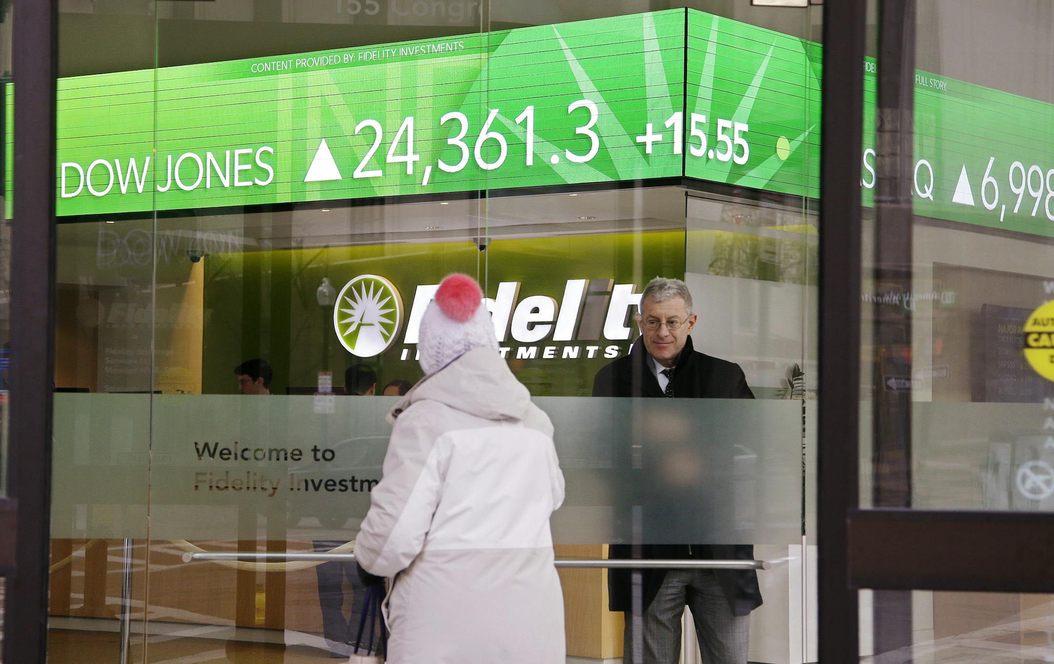 FILE - In this Feb. 6, 2018, file photo, a woman walks through the front doors at a Fidelity Investments office on Congress Street as the ticker displays stock market numbers in Boston. Federal regulators are moving to require that brokers provide their customers with detailed disclosures of their potential conflicts of interest when dispensing advice for retirement planning and other investments. (AP Photo/Stephan Savoia, File)