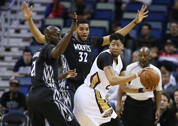 New Orleans Pelicans forward Anthony Davis, right, looks to pass against Timberwolves center Karl-Anthony Towns (32) and forward Kevin Garnett.