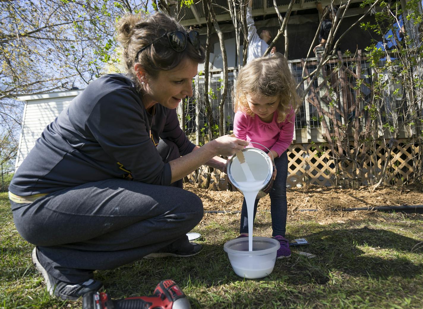 Krista Uderman, left and her daughter Brooklyn pour paint into a bucket for Janet Nelson's porch.]
TONY SAUNDERS &#xb0; anthony.saunders@startribune.com on Saturday, May 4 at Janet Nelson's home in Chaska, Minn. as a part of "Christmas in May"