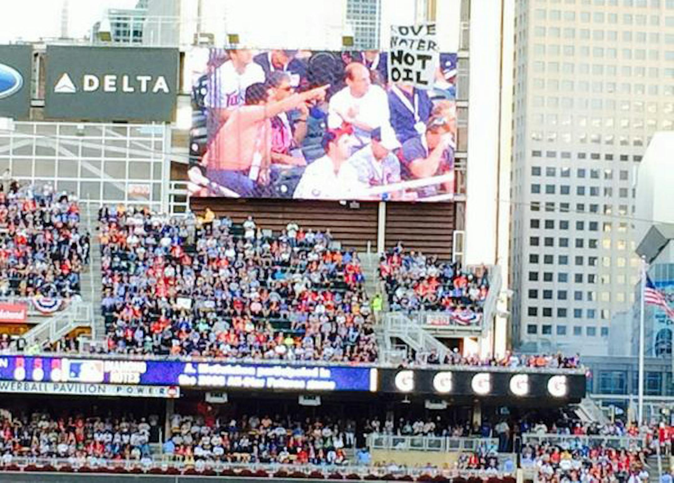 A banner reading "Love water not oil" briefly obscured the right field video board during the All Star Game at Target Field on July 15, 2014.