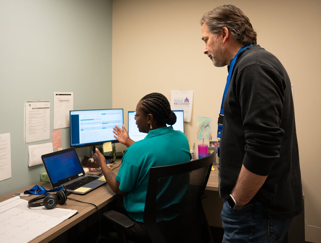 Robert Brass, diversion program manager, looks over the shoulder of Kuatree Dillard, diversion unit manager, in her office at Catholic Charities headquarters in Minneapolis.
