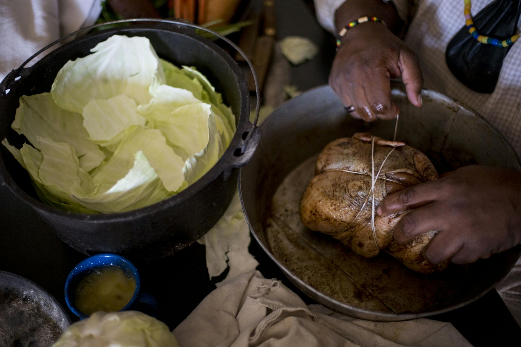 Michael Twitty binds the chicken together with twine before covering it in cabbage leaves to cook.