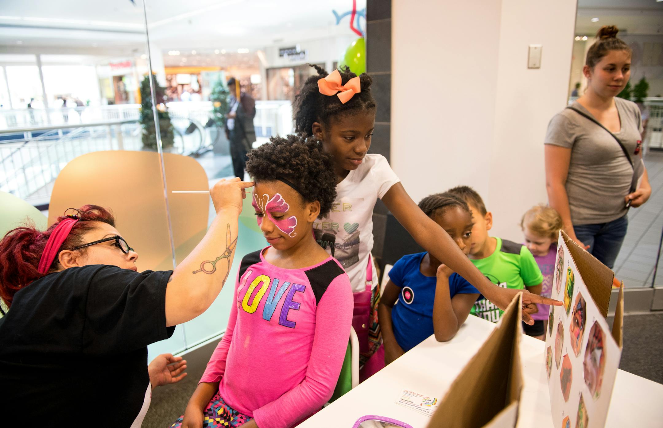 Niomi Dillard (cq), 10, sister Niayla Dillard (cq), 11, and cousin Serenity Black (cq), 5, waited in line to have their faces painted by Jenna Rod (cq) during the grand opening celebration of "Drop 'n Shop" Friday at Mall of America. ] (AARON LAVINSKY/STAR TRIBUNE) aaron.lavinsky@startribune.com A new child care drop-off service called Drop 'n Shop at the Mall of America is opening. It will give parents an option for more stress-free shopping without the kids. We photograph the grand opening cel