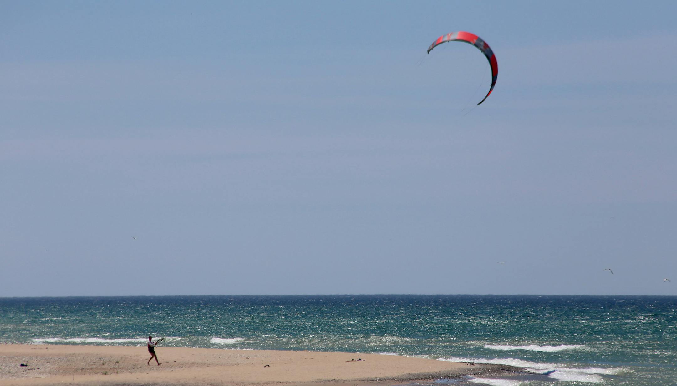 A kite-surfer prepared to launch from Point Betsie beach on Lake Michigan. The Point Betsie Lighthouse along the shore is one of the most photographed beacons in the state.