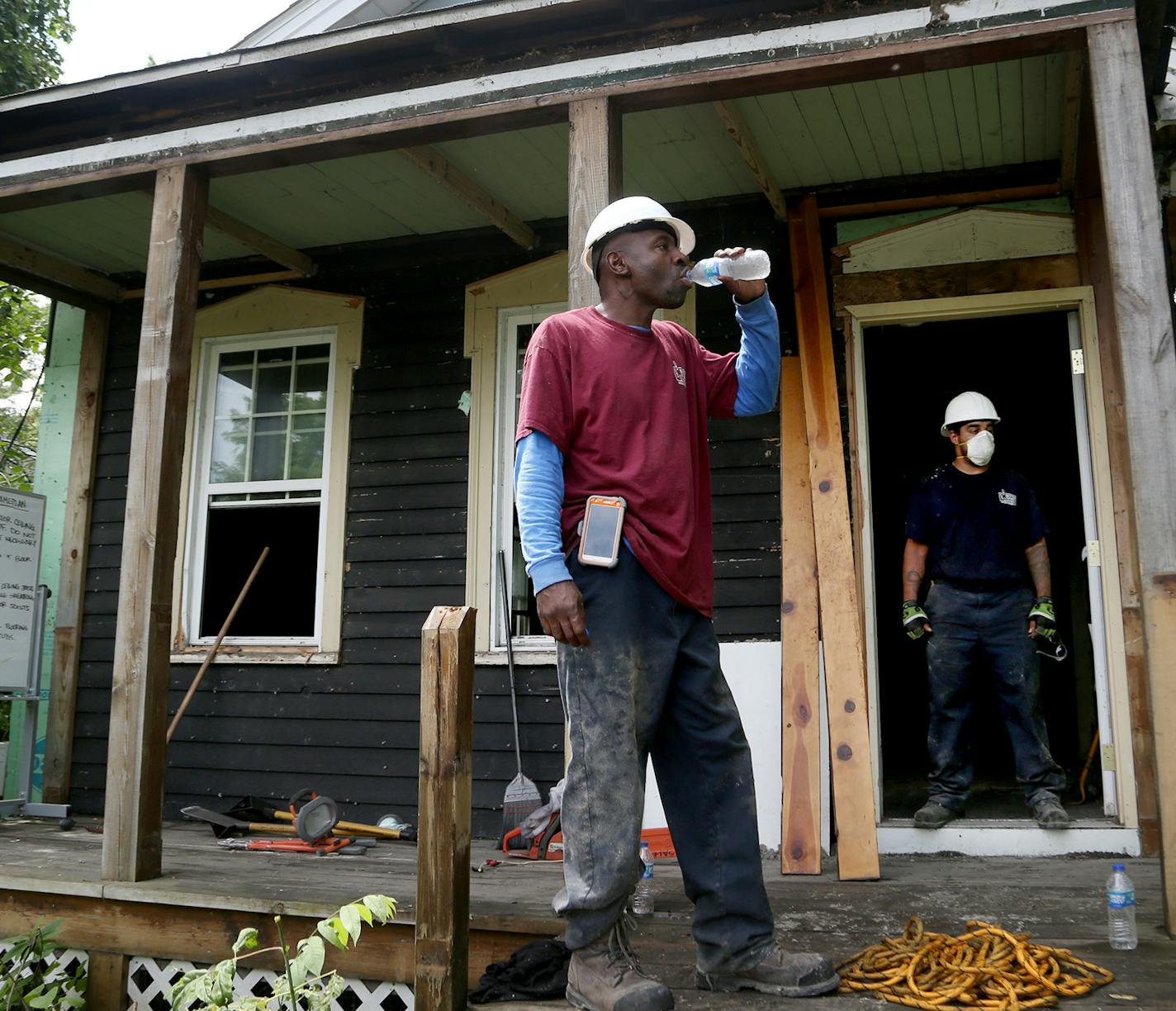 Fred Gurley, crew chief for Better Homes Minnesota, a non-profit that assists men in the community in gaining employment while helping protect the environment, takes a drink of water while breaking from disassembling a home as Josh Stewart, crew-chief-in-training, stands in the doorway Tuesday, July 18, 2017, in Roseville, MN.] DAVID JOLES &#xef; david.joles@startribune.com Roseville has commissioned the meticulous stick-by-stick, nail-by-nail deconstruction of a house to recycle it, to make a p