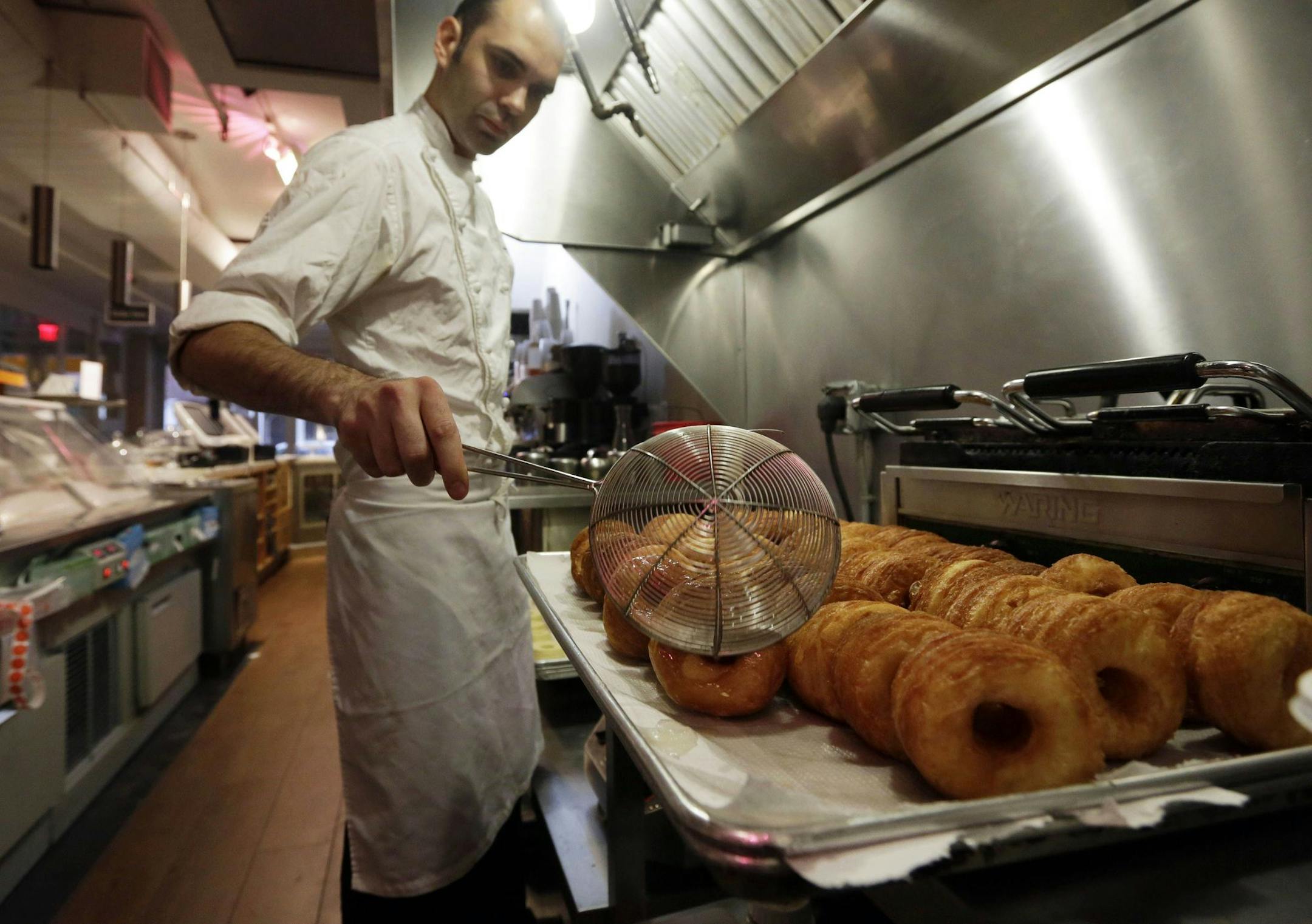 FILE - In this June 3, 2013 file photo, chef Dominique Ansel makes Cronuts, a croissant-donut hybrid, at the Dominique Ansel Bakery in New York. The mashup of a croissant and doughnut was written up and photographed by food blog Grub Street. It quickly spread online and beyond. "By the end of the first week, we had over 100 people in line," says Ansel. (AP Photo/Richard Drew, File) ORG XMIT: NYBZ202