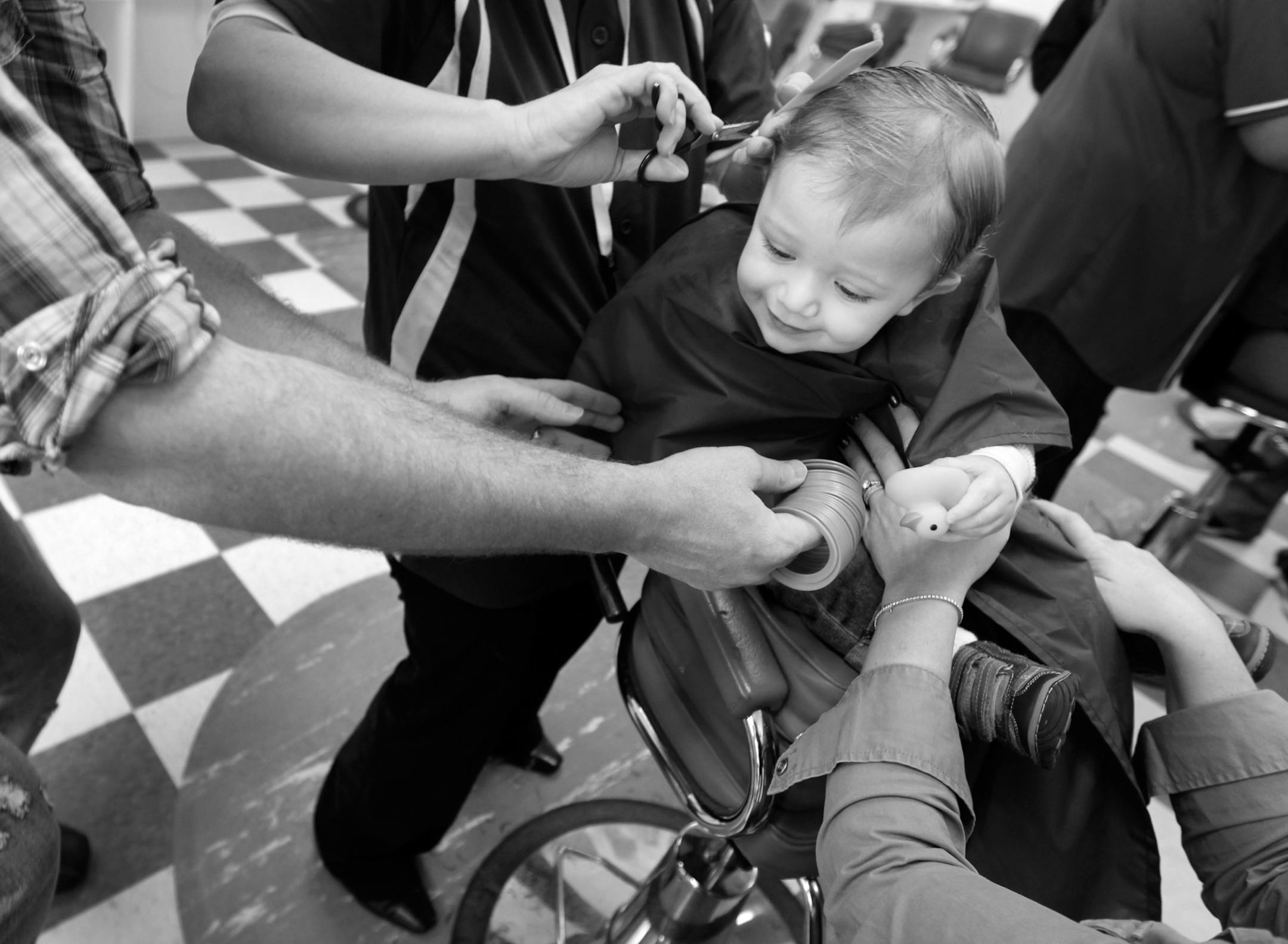 At Kid's Hair, a salon that specializes in cutting children's hair, Frank Nameny V got his first haircut at the age of 14 months. "He has got all this craziness going on. It's time," said dad Frank Nameny IV who was holding a coiled spring toy while hairstylist Jody Gacek was cutting hair. Mom Heather chipped in by holding a rubber duck toy. Frank Nameny IV wanted to be there for his son's first haircut and saved a clipping of the first cut which he did himself. He fondly remembers his own fathe