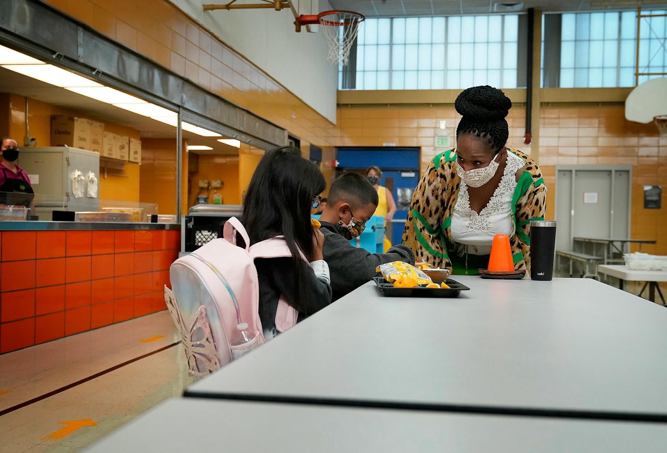 New Hoover Elementary School principal Keisha Davis chatted with siblings Evelia Ocotoxtle, a first grader, left, and Romeo Ocotoxtle, a third grader, as they ate breakfast before the start of the first day of school Tuesday in Coon Rapids.   ]
