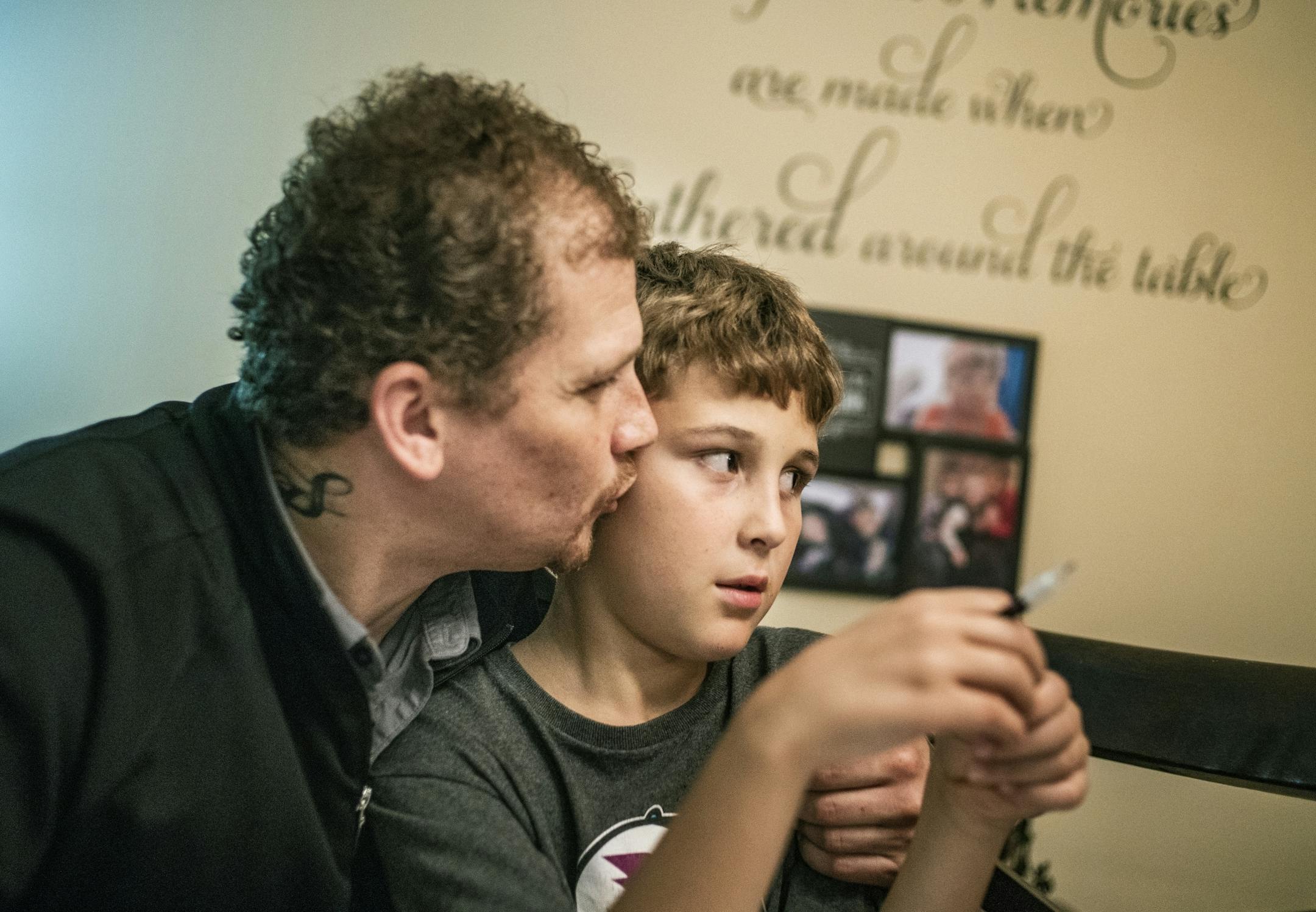 Alex Kempe show some affection while helping his oldest son Aiden,9, with his math homework.