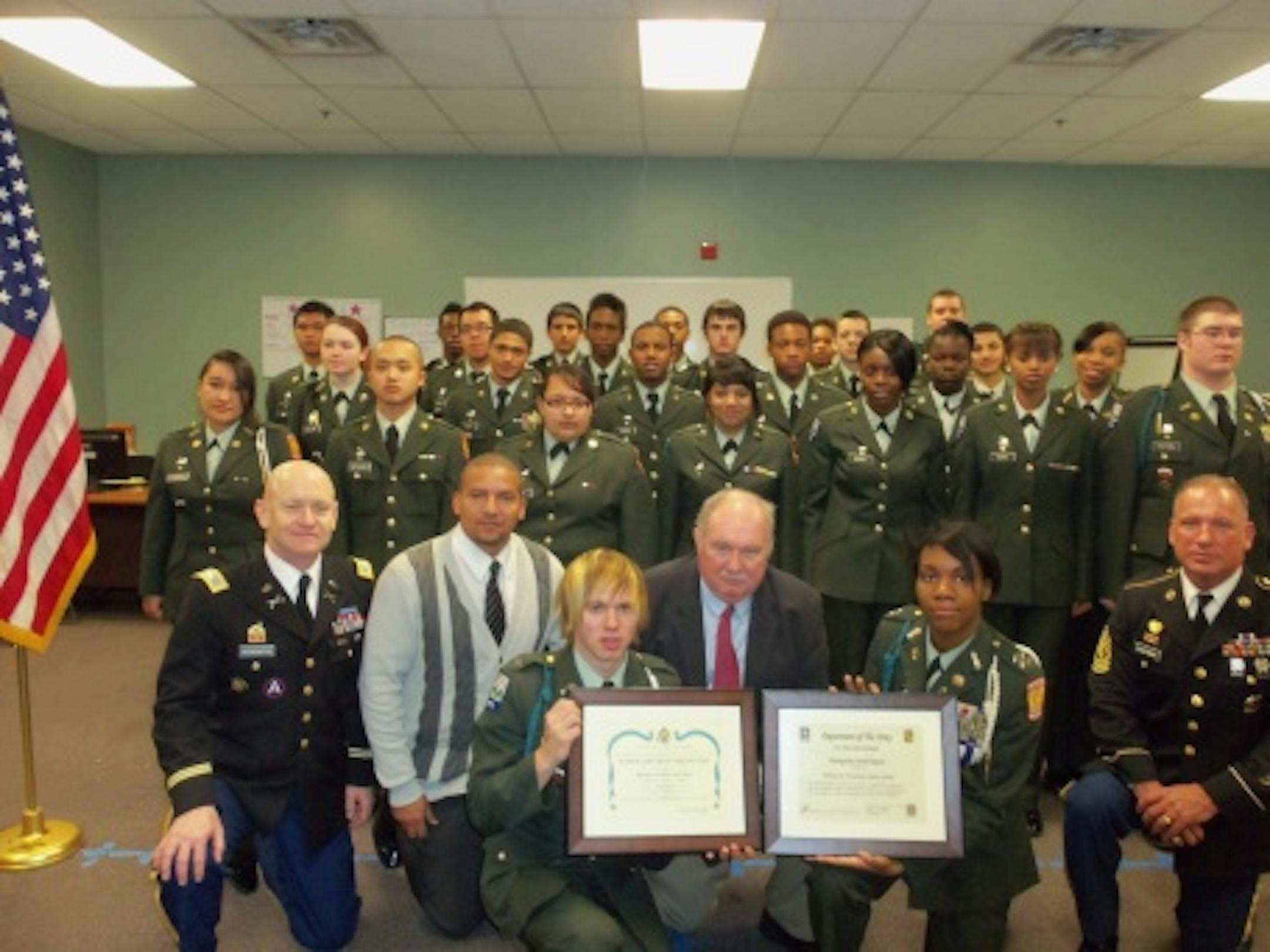 Minnesota Transitions Charter School JROTC cadets proudly display their "Honor Unit with Distinction" Award. Pictured in the front row COL (Ret) Neil Hetherington, Senior Army Instructor; Mr. James Strait, Principal, MTS Leadership/JROTC Academy; Cadet Major Ryan Gregerson; Mr. Tony Scallon, MTS District Superintendent; Cadet Lieutenant Colonel Symone Randle; 1SG (Ret) Stephen Chapman
