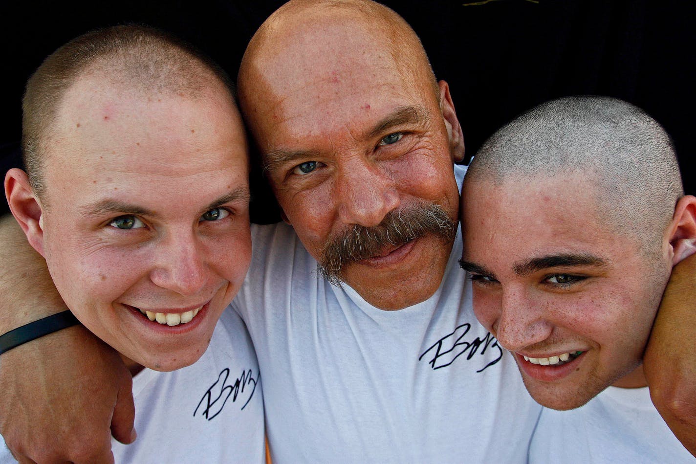 Brotherhood of Bald People founder and mission director Mike Ubl, center, hugged sons Tyris Ubl, 20, left and Alex Pearson, 20, after they had their heads shaved. The worldwide support group also embraces women and children who have lost their hair to illnesses or chemotherapy.