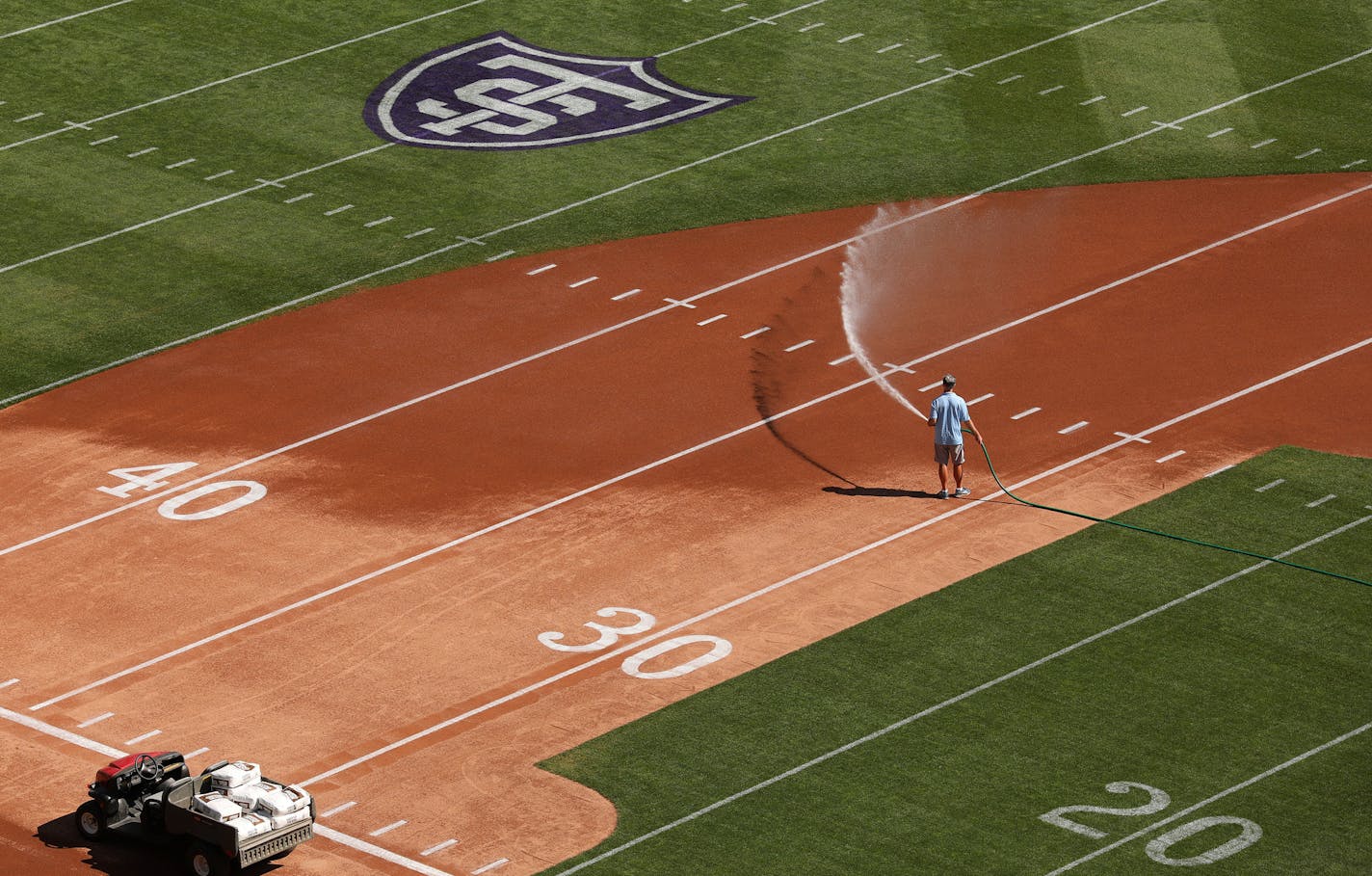 Head groundskeeper Larry DiVito sprayed down the infield as he and his crew worked to transform Target Field from a baseball to a football configuration in preparation for Saturday's game between the St. Thomas University Tommies and the St. Johns Johnnies. ] ANTHONY SOUFFLE &#xef; anthony.souffle@startribune.com Groundskeepers worked to transform Target Field from a baseball to a football configuration in preparation for Saturday's game between the St. Thomas University Tommies and the St. John