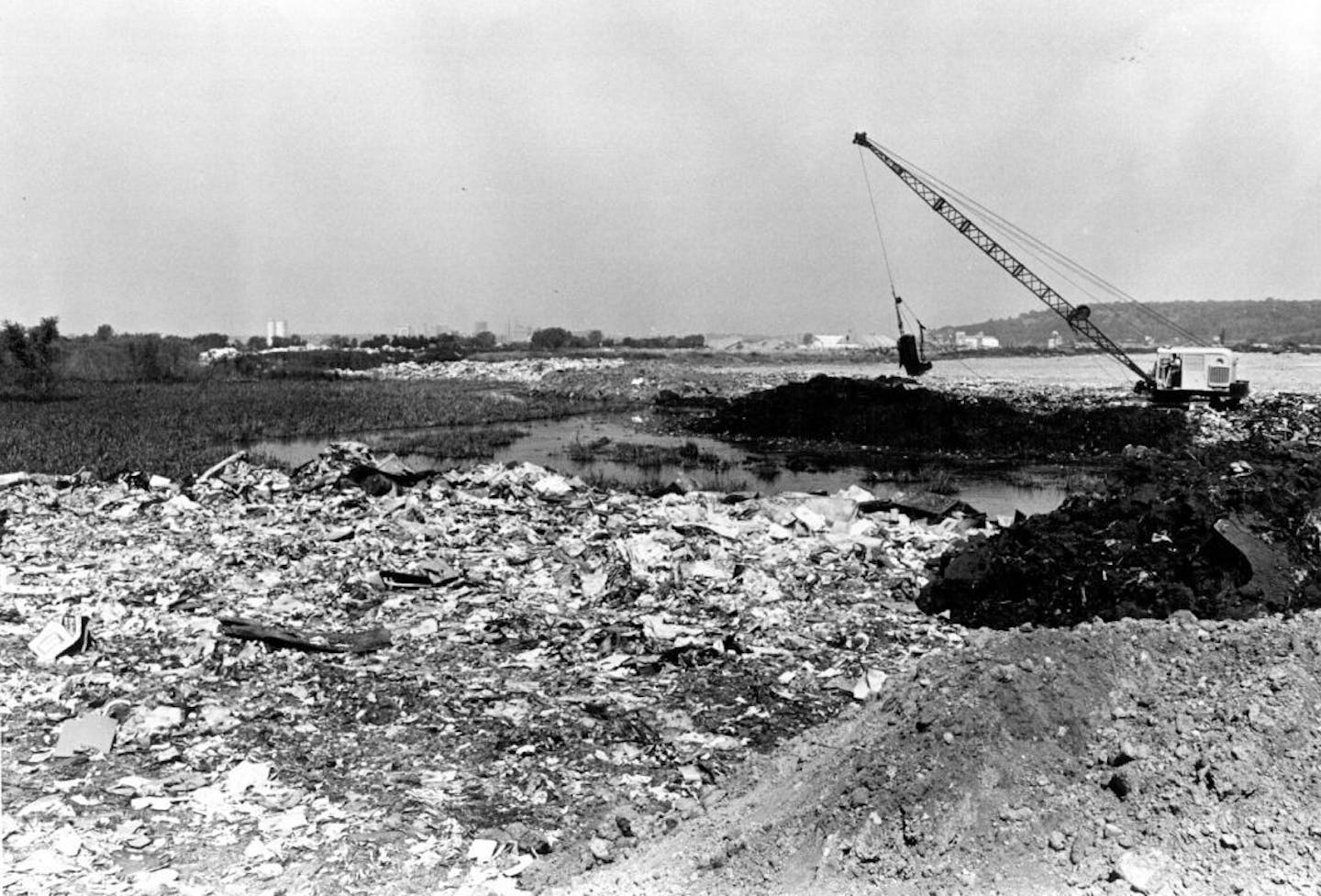 August 2, 1967 REFUSE FROM ST. PAUL HOMES WAITS TO BE BURIED "We intend to dress up Pig's Eye" The sprawling 200-acre Pig's Eye Municipal Landfill on St. Paul's far south side is the mecca for 600 tons of garbage and rubbish that roll daily through its gates. More than two dozen crane operators working two eight-hour split shifts dig "cells" to bury the refuse - most of it from 49,000 St. Paul households. The cells, roughly comparable with a city block, are dug 10 feet below Pig's Eye's sludgy s