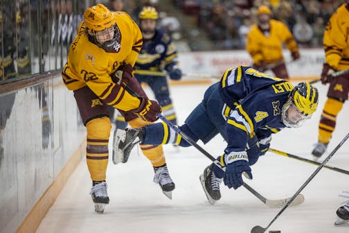 Minnesota's forward Bryce Brodzinski (22), left, and Michigan's forward Gavin Brindley (4) battle for the puck during the first period as Minnesota takes on Michigan at 3M Arena at Mariucci in Minneapolis, Minn., on Saturday, Jan. 21, 2023. ] Elizabeth Flores • liz.flores@startribune.com