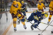 Minnesota's forward Bryce Brodzinski (22), left, and Michigan's forward Gavin Brindley (4) battle for the puck during the first period as Minnesota ta