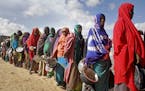 FILE - In this Saturday, May 18, 2019 file photo, newly-arrived women who fled drought line up to receive food distributed by local volunteers at a ca